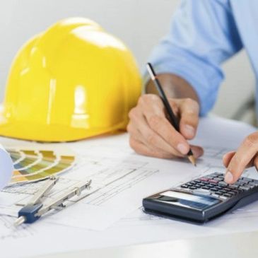 Engineer calculating with blueprints and hard hat.