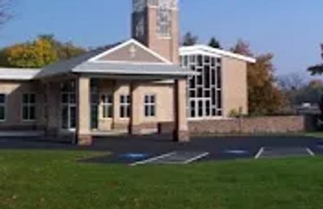 A modern church building with a tall clock tower under a clear blue sky.
