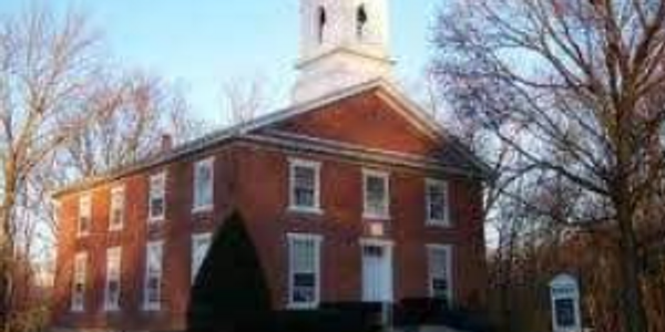 Historic brick church with a white steeple under a clear blue sky.
