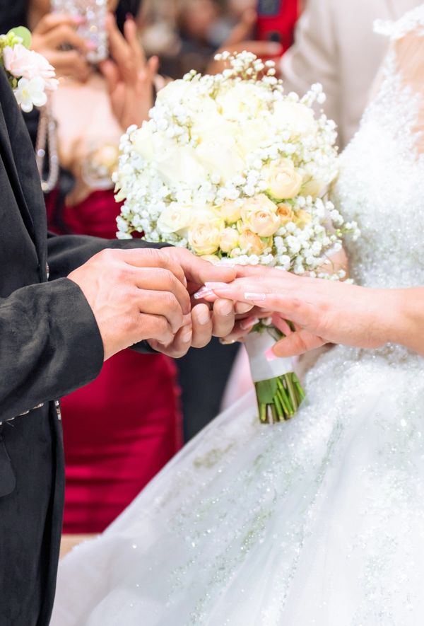 Groom placing ring on bride's finger during wedding ceremony.