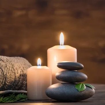 Stacked black stones and lit candles with a towel.