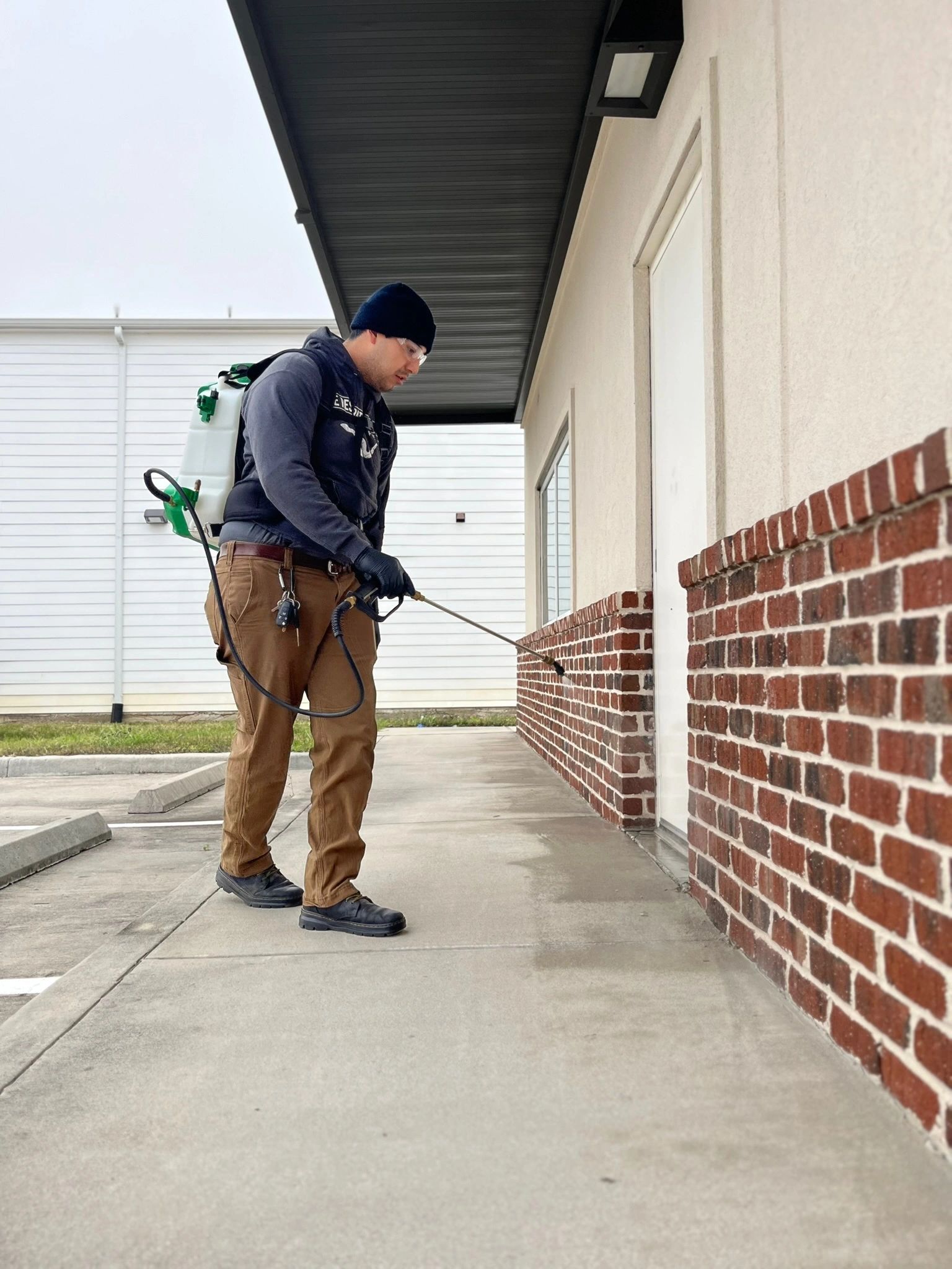 Commercial pest control technician performing an exterior pest treatment at a Houston restaurant.