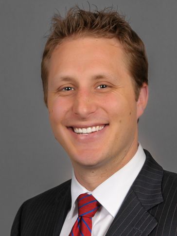 Smiling man in suit and red striped tie.
