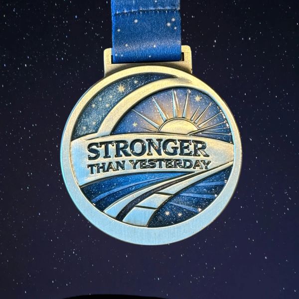 Stronger Than Yesterday medal featuring an open path and horizon symbolizing progress.