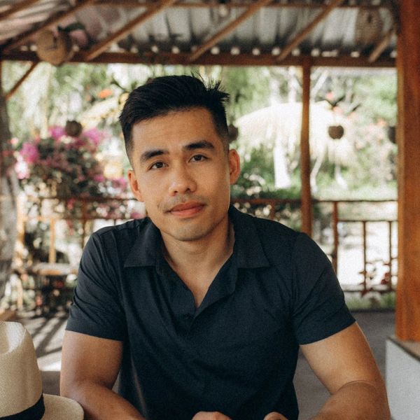 A man in a black shirt sitting outdoors in a relaxed setting.