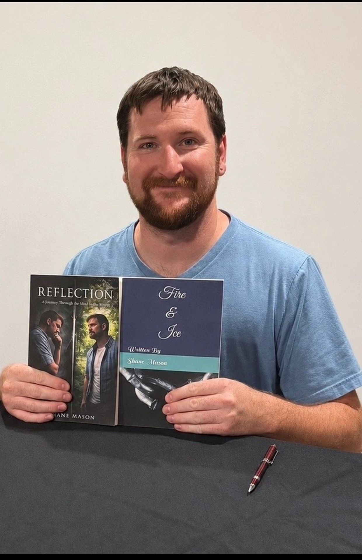 Man holding two books he wrote.