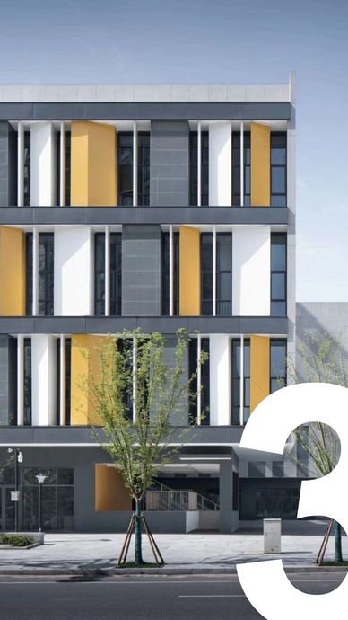 Modern building facade with yellow and white panels and young trees.