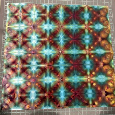 Colorful tie-dye fabric with symmetrical starburst patterns.