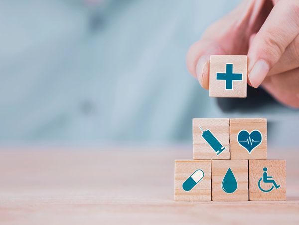 Businessman chooses an emoticon icons healthcare medical symbol on wooden block,