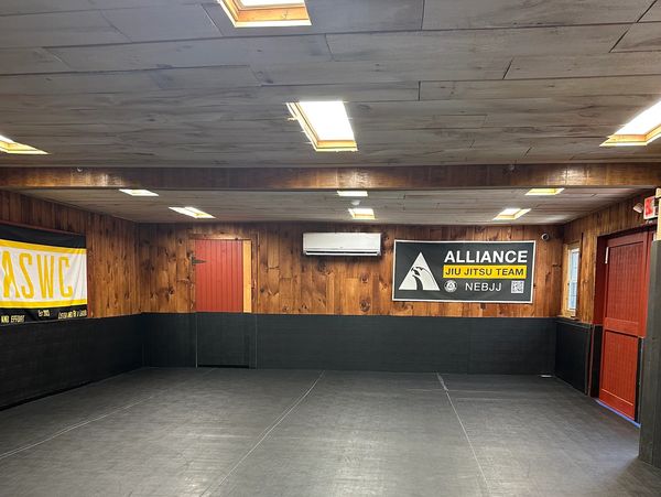 Empty martial arts training room with padded floors and wooden walls.