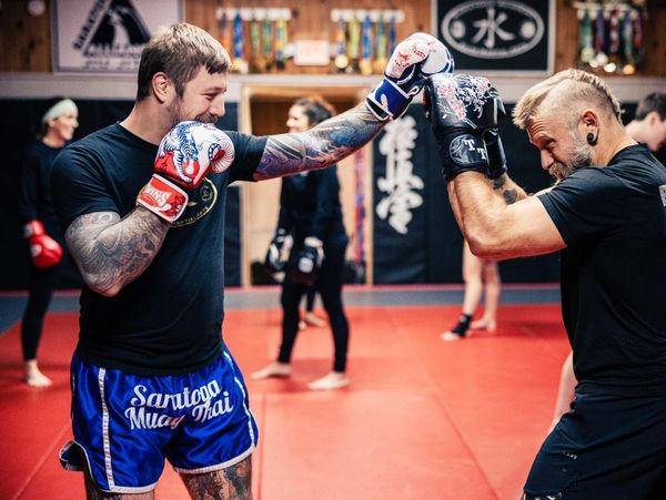 Two men sparring with boxing gloves in a martial arts gym.