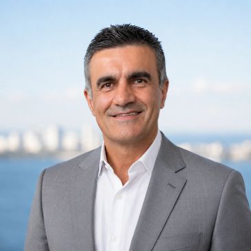 Man in a gray suit smiling outdoors.