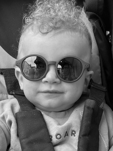 Baby wearing sunglasses in a stroller.