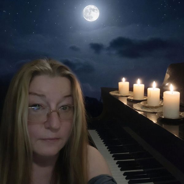 Christine Parkhurst sitting by the piano in candlelight.