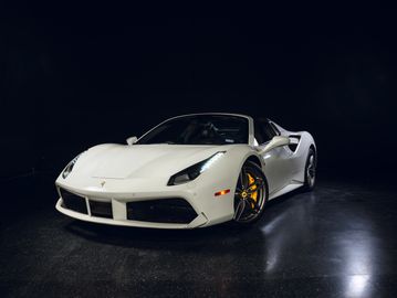White luxury sports car with yellow brake calipers in a dark studio.