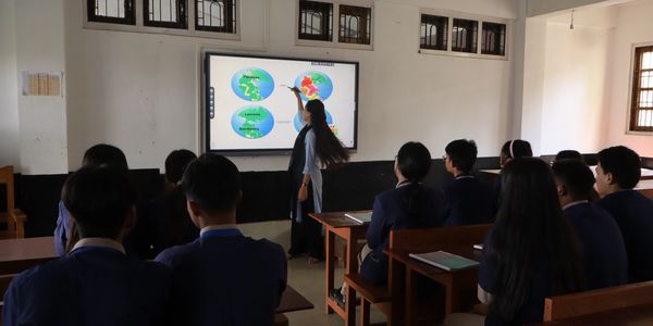 Teacher explaining continental drift theory using digital map in classroom.