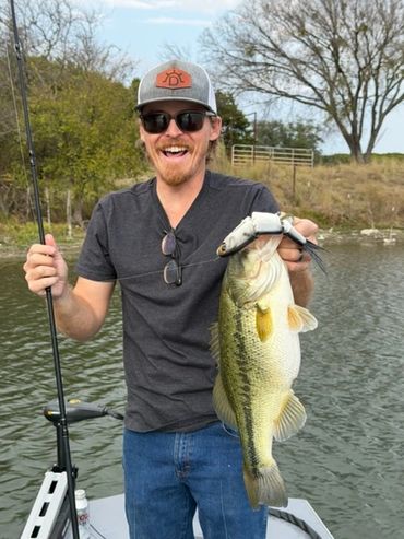 Man proudly holding a large fish he caught while fishing on a boat.