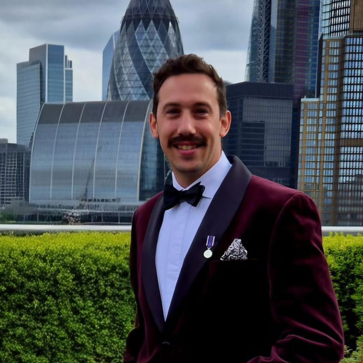 Man in a tuxedo with city skyline background.