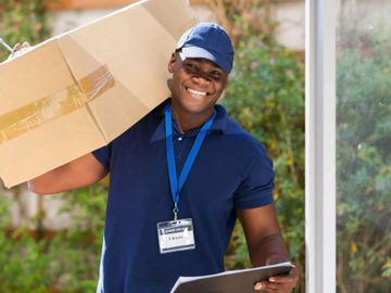 Smiling delivery man carrying a box and holding a clipboard.