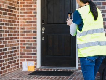 Delivery person photographing packages left at a doorstep.