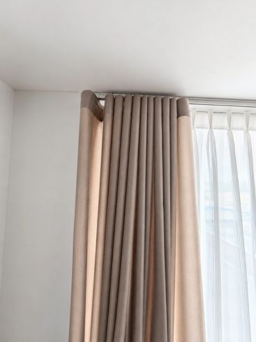 Elegant beige curtains neatly hanging in front of sheer white drapes.