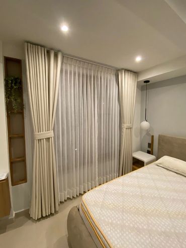 Cozy bedroom with beige curtains and soft lighting.