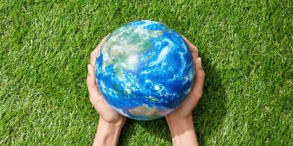 Grass with hands holding a globe