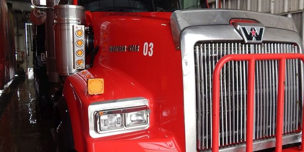 Close-up of a red Western Star truck's front side inside a garage.