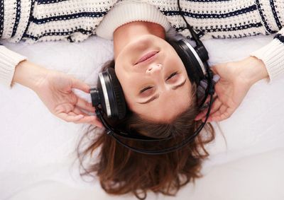 Woman lying down enjoying music with headphones on.