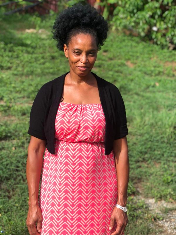 Woman in a patterned red dress and black cardigan standing outdoors.