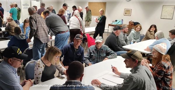 A group of people sitting around a table at a watershed stakeholder meeting. 