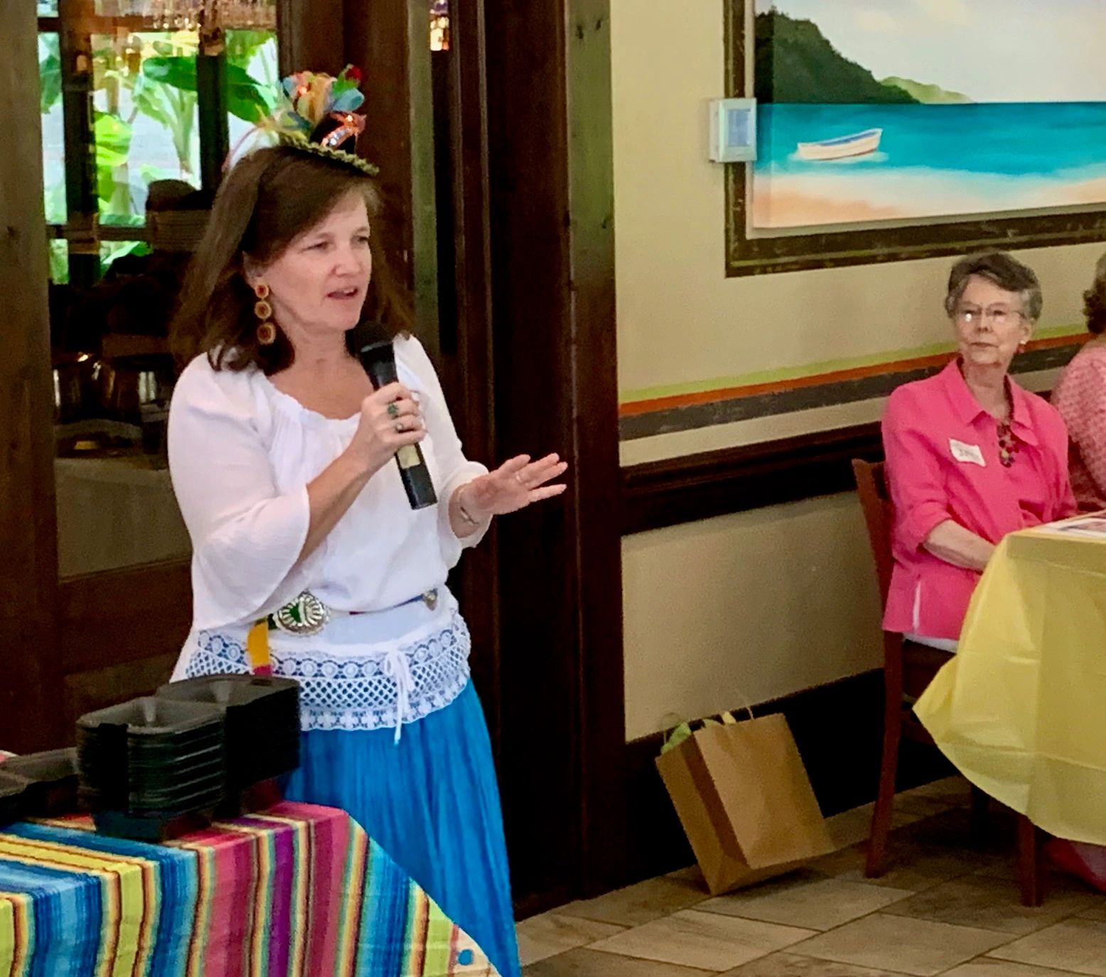 Woman speaking into a microphone at a colorful indoor event.