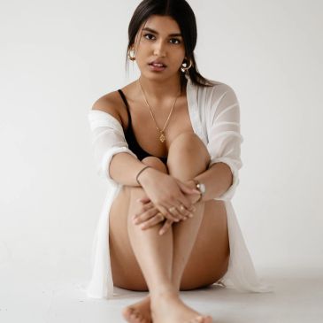 Woman sitting on floor wearing white cover-up and black outfit.