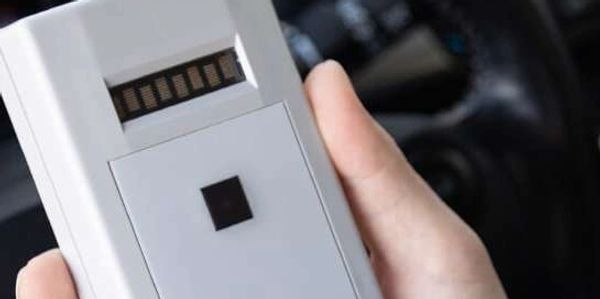 A person holding an alcohol tester in their hand.