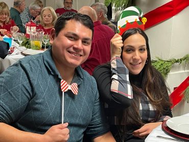 A cheerful couple enjoying a festive holiday gathering with props and decorations.