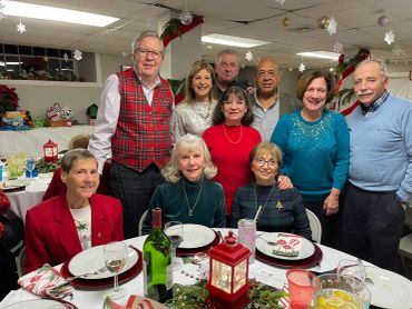 Group of ten adults gathered around a festive holiday dinner table.