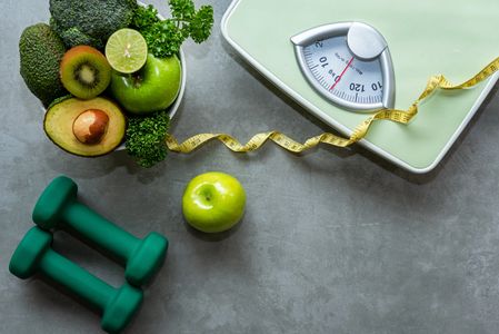 A scale, weights, tape measure and healthy food relating to Weight management hypnosis treatment 