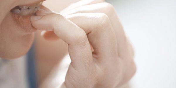 A person putting their hands in their mouth to bite their nails in a state of anxiousness.