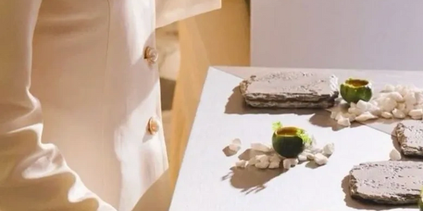 Elegant servers in cream attire prepare a refined display with stone plates and decorative elements.