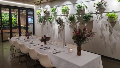 Elegant dining table set with white chairs and wall-mounted plants.
