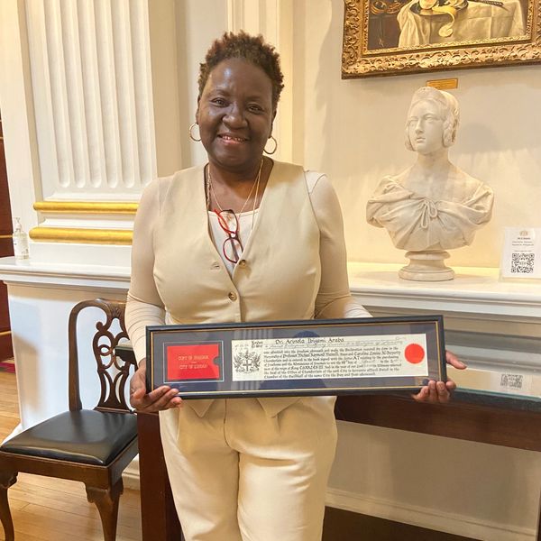 Woman proudly holding a framed certificate indoors.