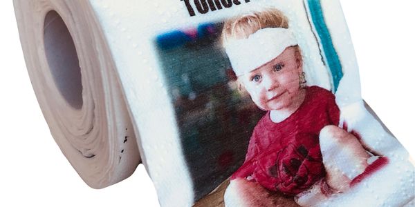 Toilet paper roll printed with a photo of a baby wearing a red shirt and white headband.