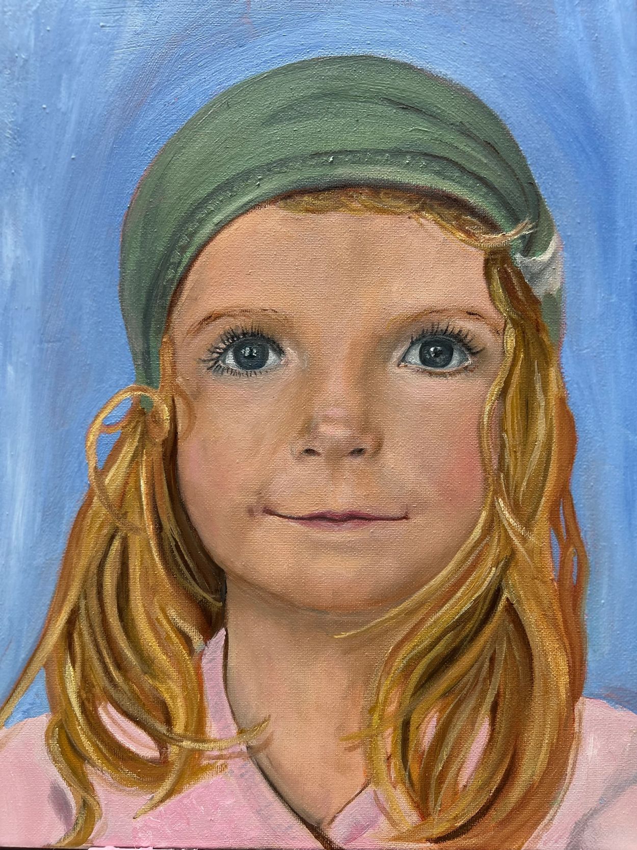 Portrait of a young girl with a green hat and blonde hair.