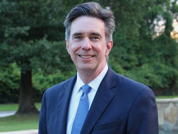 Man in suit smiling outdoors.