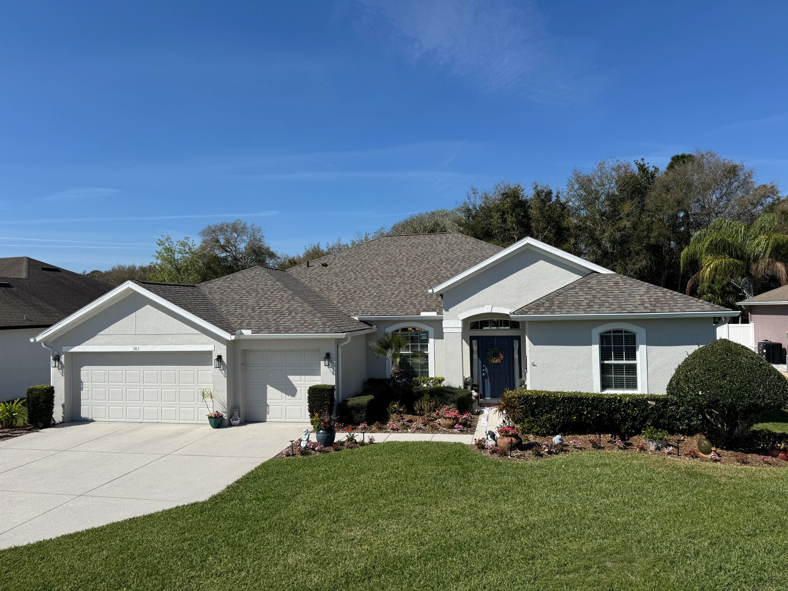 White suburban house with a well-kept lawn and clear blue sky.