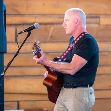 Man playing guitar and singing into microphone.