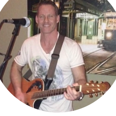 Man playing an acoustic guitar and smiling.