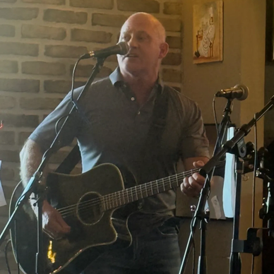 Man playing guitar and singing indoors.