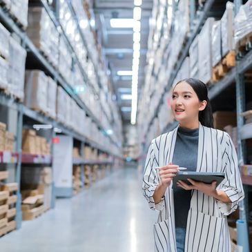 Woman using tablet in warehouse aisle.