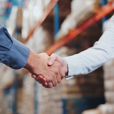 Two people shaking hands in a warehouse.